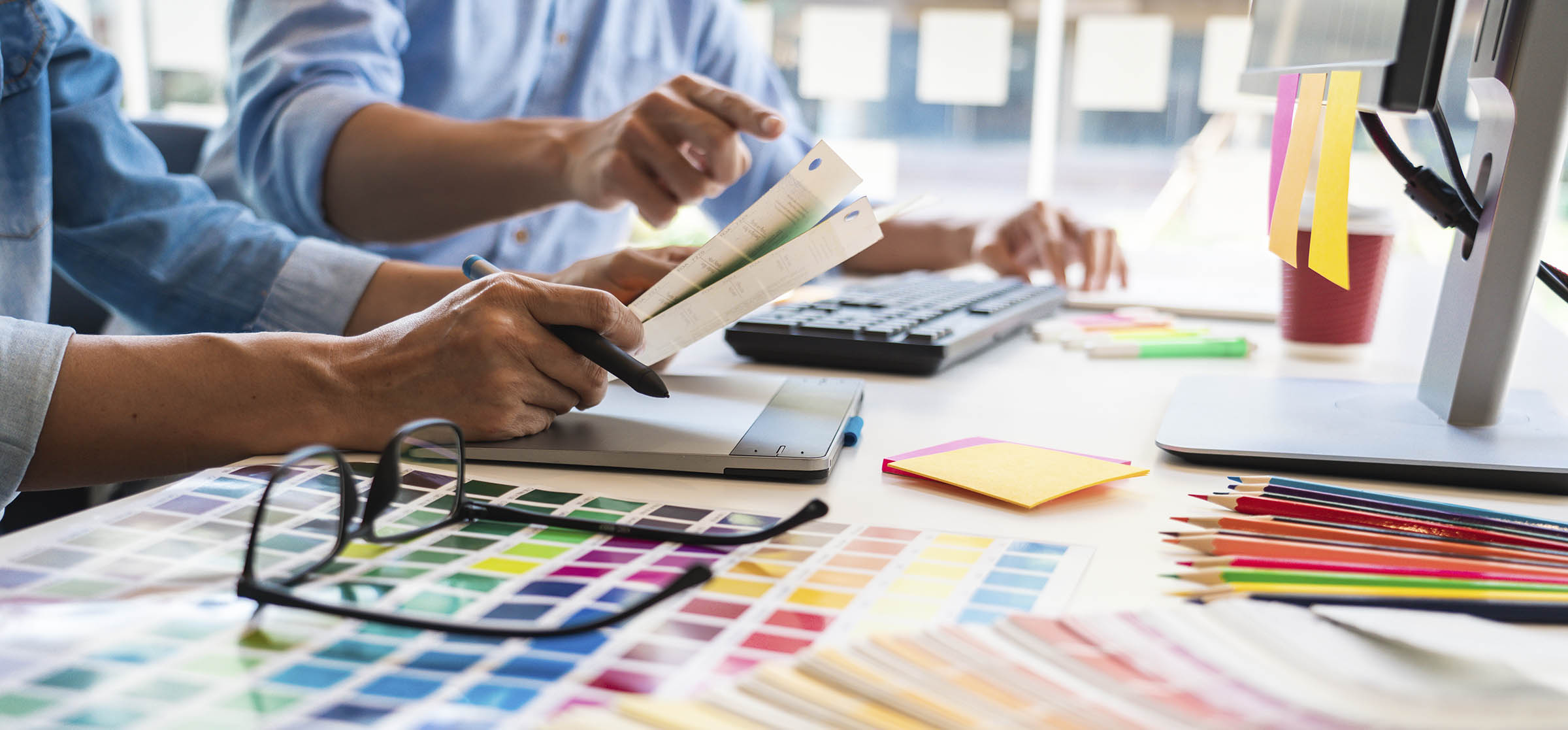 Professionista grafico e programmatore, che sceglie i campioni della tavolozza dei colori Pantone per un progetto sul computer desktop dell'ufficio.